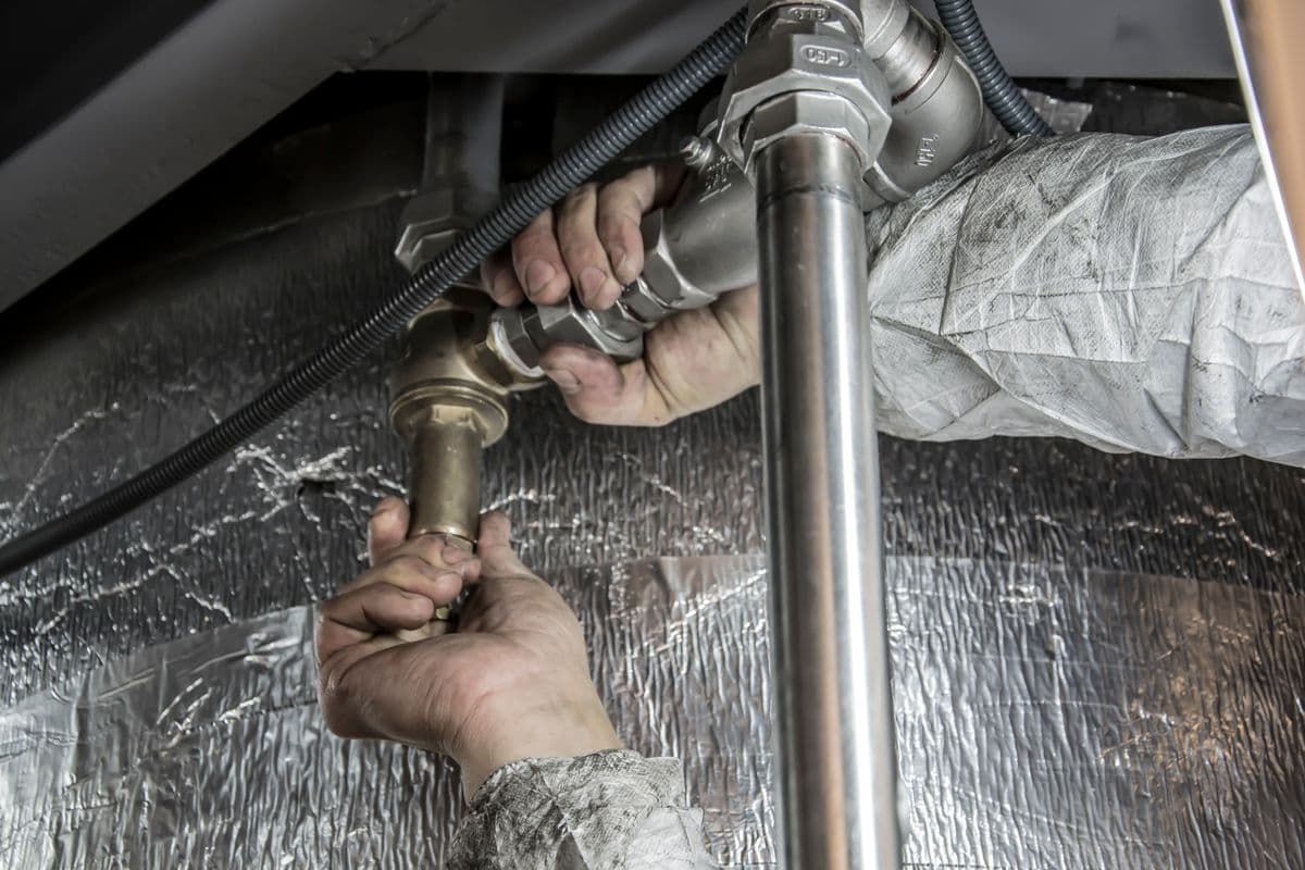 Plumber fitting pipes under a sink
